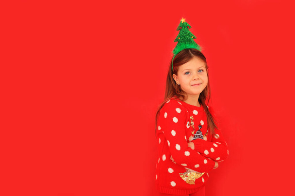 Pieni tyttö uusi vuosi pusero punaisella taustalla joulukuusi - Valokuva, kuva