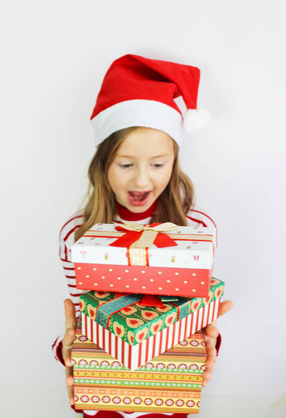 Beautiful girl red sweater Christmas and New year gift. Happy small girl in Santa s hat has a Christmas. - Φωτογραφία, εικόνα