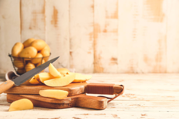 Raw potatoes with knife and cutting boards on wooden table - Photo, Image