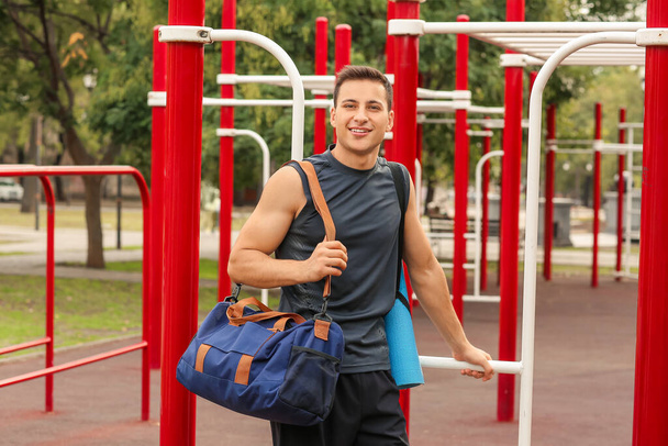 Junger Mann mit Tasche auf Sportplatz - Foto, Bild