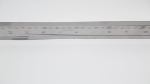 Panoramique rapide de la règle en acier inoxydable avec pouces et centimètres sur blanc  - Séquence, vidéo