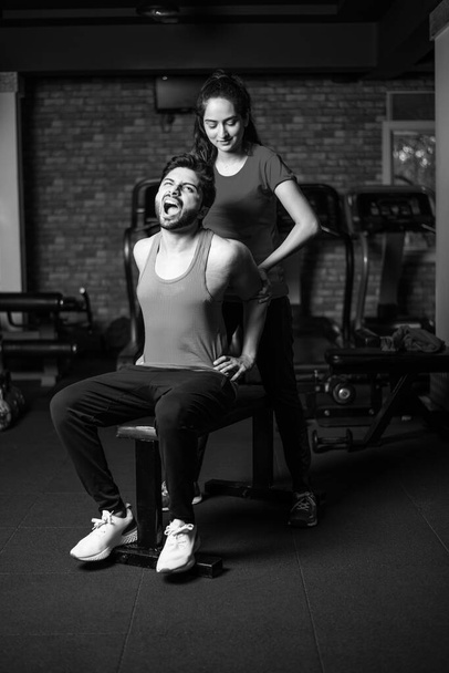 sporty Indian asian young couple stretching in gym post exercise for cooling down, improving flexibility - Photo, Image