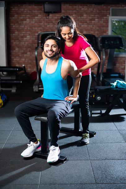 sporty Indian asian young couple stretching in gym post exercise for cooling down, improving flexibility - Photo, Image