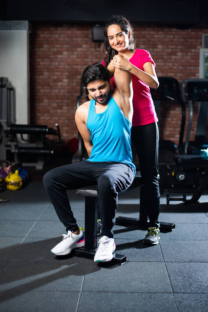 sporty Indian asian young couple stretching in gym post exercise for cooling down, improving flexibility - Foto, Imagen