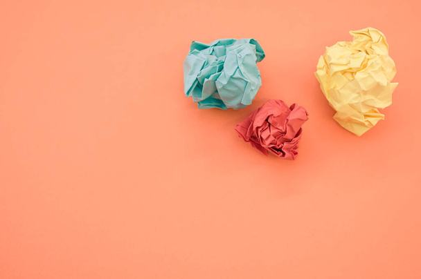 A top view of green, yellow, and red crumpled papers on orange background - Foto, imagen