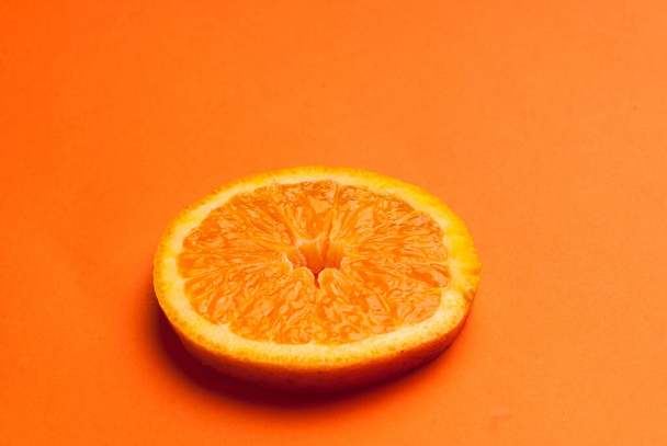 A closeup shot of a slice of orange on an orange background - Foto, imagen