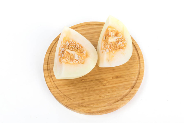 A cut fresh melon on a wooden board isolated on a white background - 写真・画像