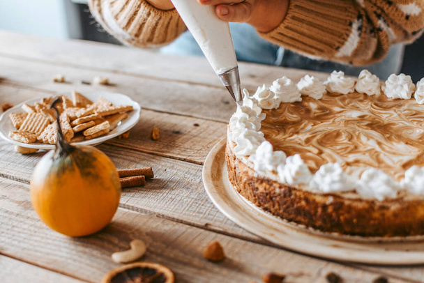 A decoration of a yummy pumpkin cheesecake with cream - Фото, зображення