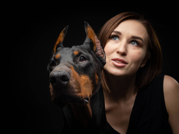 Portrait of a Doberman dog with a girl owner. Isolated Studio photo on a black background. - Photo, Image