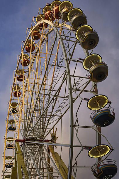 A vertical low angle shot of a Ferris wheel under a blue sky - Photo, image