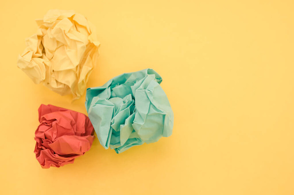 A top view of green, yellow, and red crumpled papers on yellow background - 写真・画像