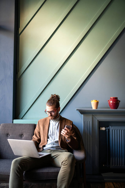 Επιτυχημένος νεαρός όμορφος επιχειρηματίας πληκτρολογώντας στο laptop στο χώρο εργασίας - Φωτογραφία, εικόνα