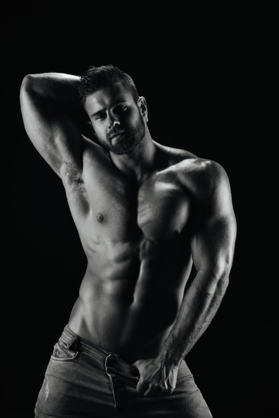 Мужчина модель фитнеса Константин Камынин позирует без рубашки на черном фоне - Фото, изображение