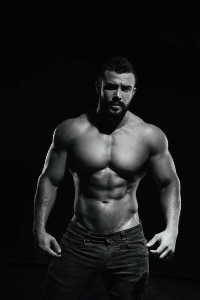 Fitness männliches Modell steht auf schwarzem Hintergrund - Foto, Bild