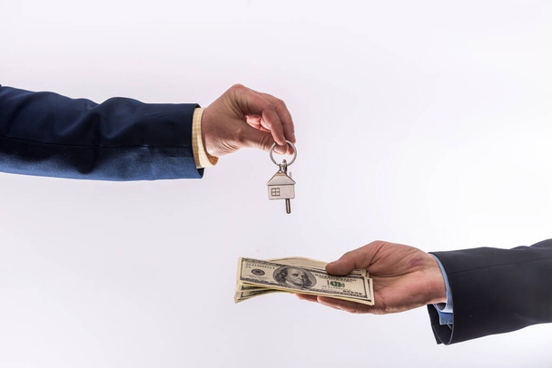 Zwei Geschäftsleute führen einen Kauf- oder Mietvertrag für ein Haus aus und tauschen Dollars und Schlüssel für die Wohnung aus. Verkauf nach Hause - Foto, Bild