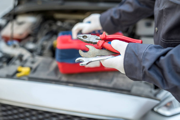 Auto mechanic in car repair holding wrench key and tools. automobile diagnostic - Photo, Image