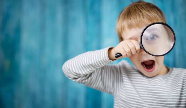 Little boy shocked looking through a magnifying glass - Fotoğraf, Görsel