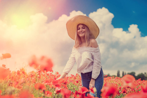 bella giovane donna in un cappello di paglia in un campo di papavero in estate. natura di bellezza - Foto, immagini