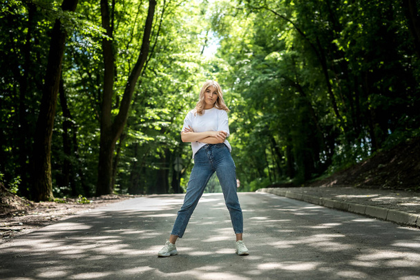joven dama en jeans y una camiseta blanca tiene un gran tiempo en la naturaleza en el bosque. verano - Foto, Imagen