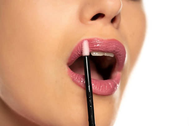 Closeup of woman applying lipgloss on white background - Valokuva, kuva
