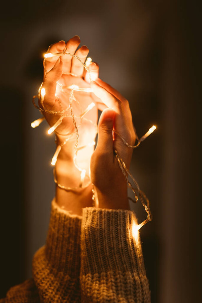 Woman holding christmas lamps in hands  - Fotoğraf, Görsel