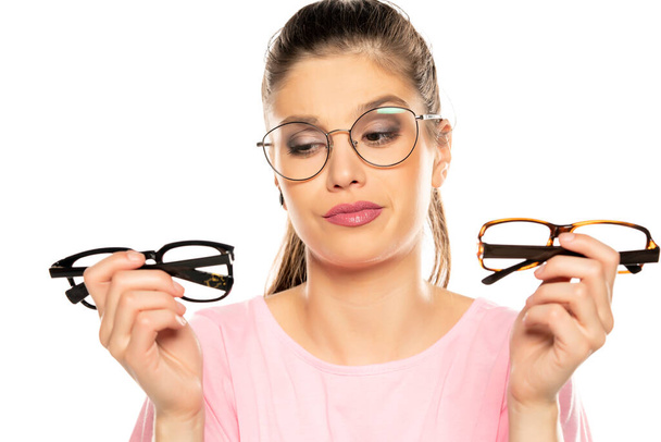 eine junge Frau wählt einen Rahmen für ihre neue Brille auf weißem Hintergrund - Foto, Bild
