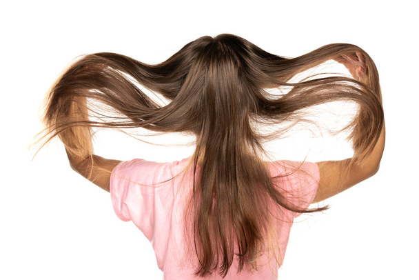 the look behind the young woman lifts her fluttering long straight hair against a white background - Photo, image