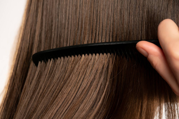 Closeup of young woman combing her hair - Foto, Bild