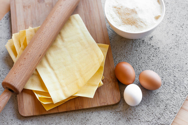 Ingredients for homemade lasagna. Rolling pin, flour, eggs and fresh lasagna sheets. Selective focus. Top view. - Foto, immagini
