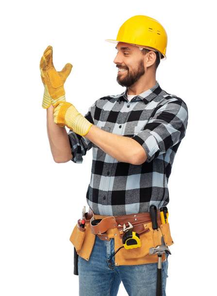 happy male worker or builder in helmet and gloves - Fotó, kép