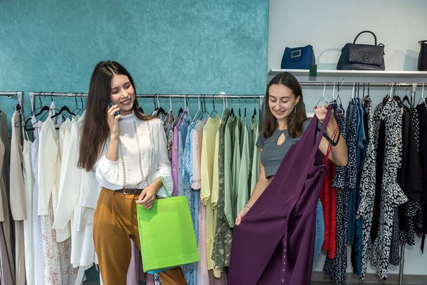 Two friends choosing a new cloth in a clothing boutique. Buy and sale - Photo, Image