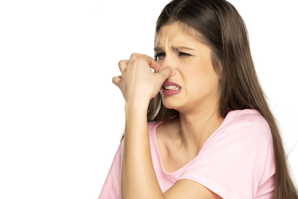 Giovane donna disgustata pizzicando il naso su sfondo bianco - Foto, immagini