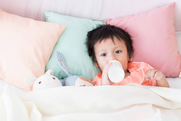 Schöner Kleinkind-Junge legt sich mit Milchflasche ins Bett - Foto, Bild