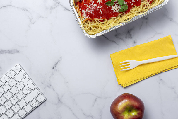 Lunch at workplace homemade and healthy spaghetti with tomato and cheese on work table with computer keyboard. Home food for office concept. Take away food - Fotografie, Obrázek