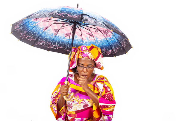 白い背景に傘を差し込み咳をしながら立つ伝統衣装の熟女. - 写真・画像