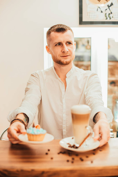 barista handing a cup of cappucino or late to customer looking at camera smiling. Brewing fresh coffee for great taste. - Фото, зображення