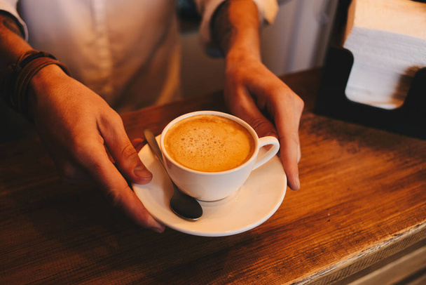 the barista holds a cup of delicious coffee. - Photo, image