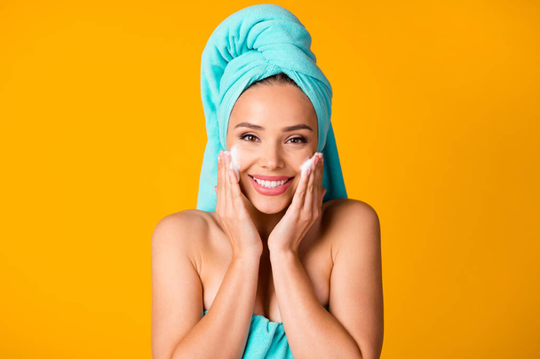 Portrait of young smiling cheerful beautiful woman girl female wiping face using lotion isolated on yellow color background - Φωτογραφία, εικόνα