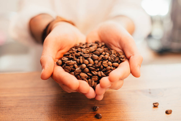 coffee beans in hands on table - Fotó, kép