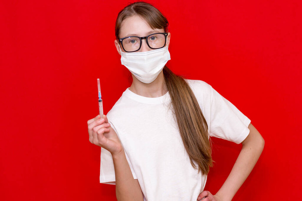 Teenage girl coronavirus medical mask with a syringe in his hands.Studio shot. - Photo, Image
