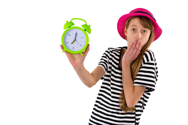 Chica sorprendida sosteniendo alarma Reloj, aislado sobre fondo blanco. Retrato de adolescente caucásico mostrando reloj despertador verde. - Foto, imagen