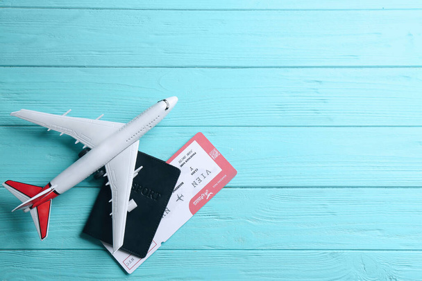 Toy airplane and passport with ticket on light blue wooden background, flat lay. Space for text - Φωτογραφία, εικόνα