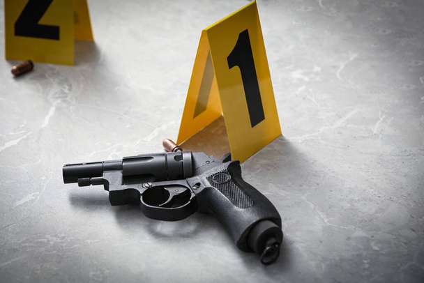Handgun and crime scene marker on light grey marble table - 写真・画像