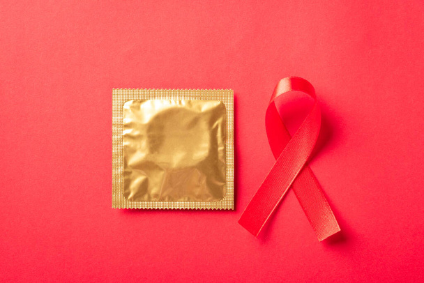 Red bow ribbon symbol HIV, AIDS cancer awareness and condom with shadows, studio shot isolated on red background, Healthcare medicine sexually concept, World AIDS Day - Valokuva, kuva