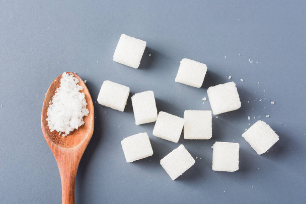 White sugar cube sweet food ingredient and sugar in spoon, studio shot isolated on a gray background, Minimal health high blood risk of diabetes and calorie intake concept - Fotografie, Obrázek