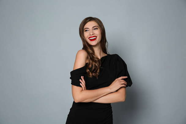 Happy woman in black dress on grey background. Christmas party - Foto, immagini