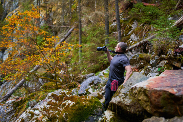 Professional nature photographer in a picturesque environment, with mountains, forest and caves - Foto, imagen