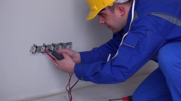 electricista hombre comprobar toma de corriente eléctrica con dispositivo especial en el nuevo apartamento. 4K - Metraje, vídeo