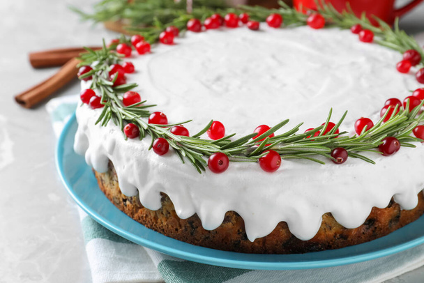 Traditional Christmas cake decorated with rosemary and cranberries on light grey marble table, closeup - Fotoğraf, Görsel