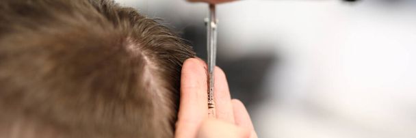 Hands of hairdresser with scissors make short haircut to man in beauty salon closeup - Foto, afbeelding